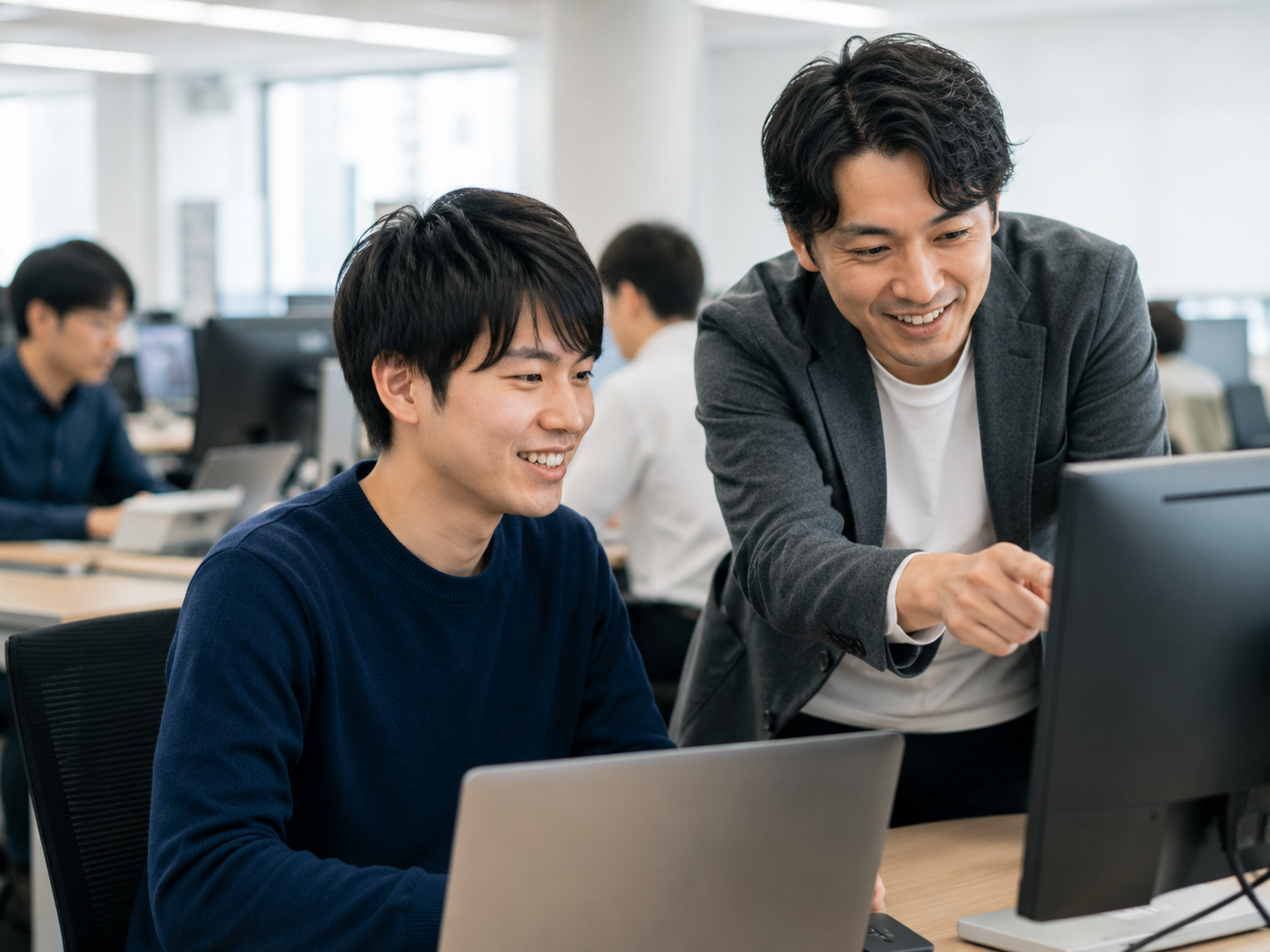 先輩社員から実務の指導を受けるエンジニア